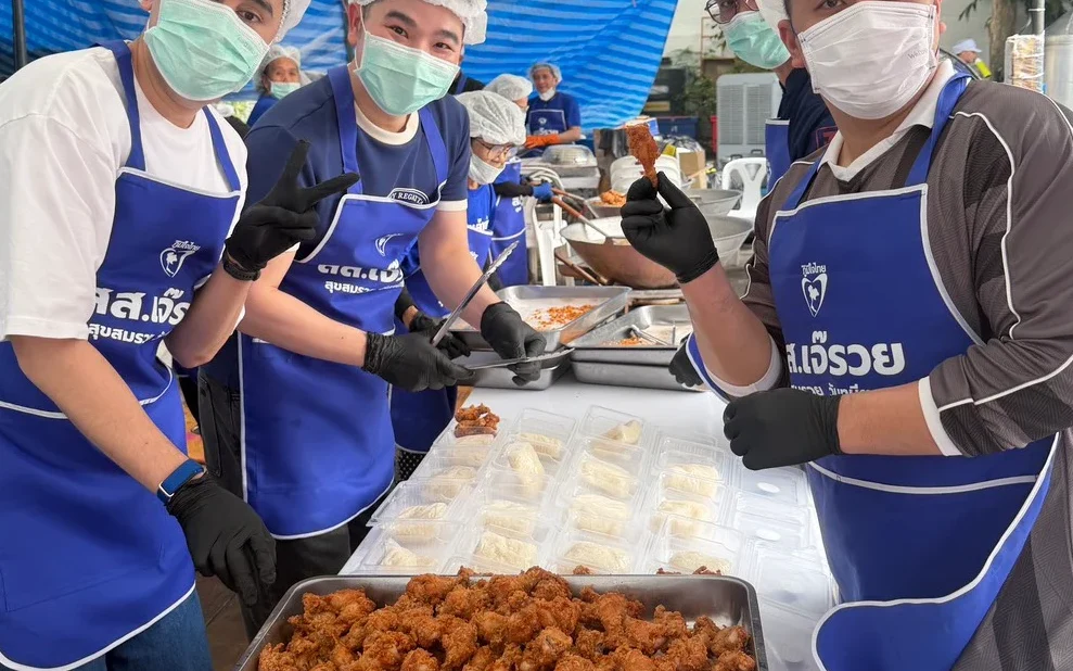 Masked volunteers prepare and serve food at a community kitchen.