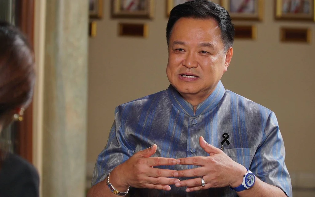 Anutin speaks during an interview, wearing a blue traditional-style shirt.