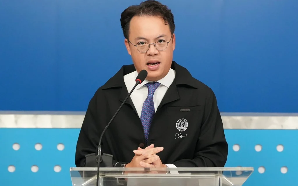 A man speaking at a podium with a blue background.