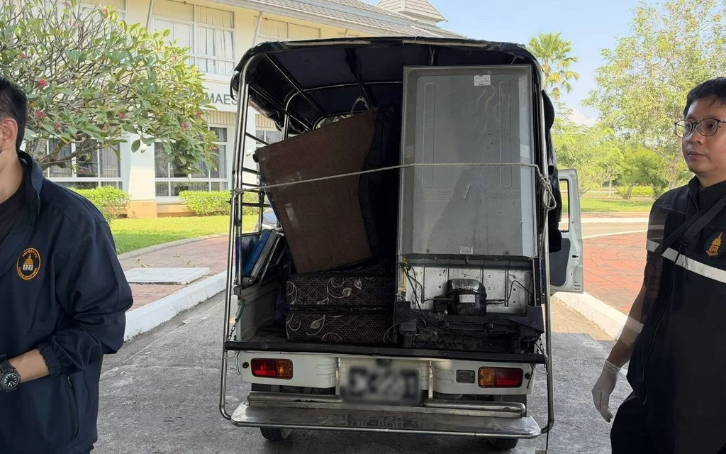 Customs officers stand beside a truck loaded with furniture.