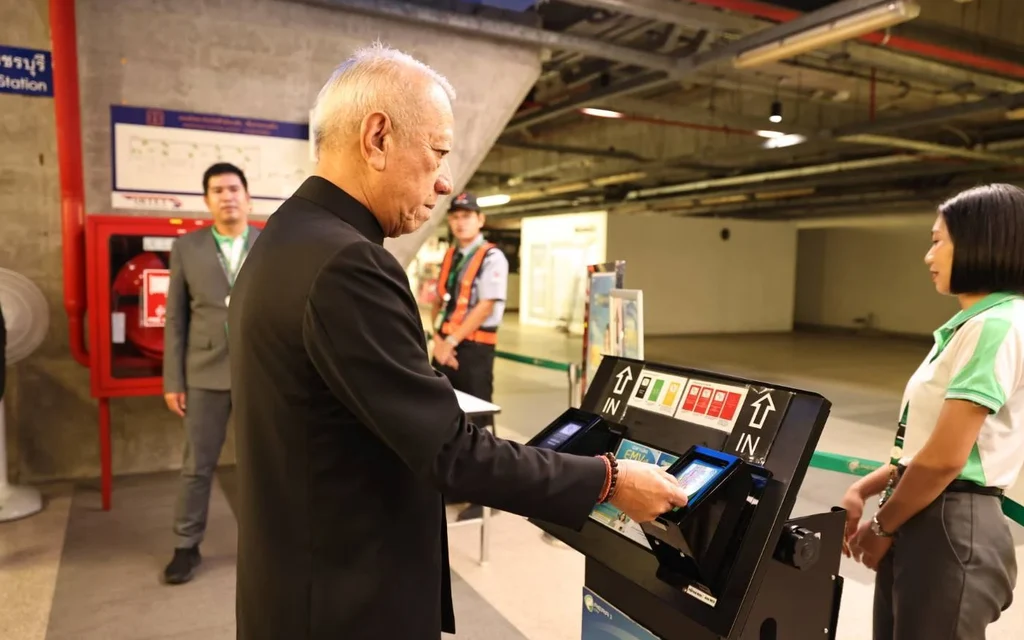 A man using a ticket machine at a Bangkok train station.