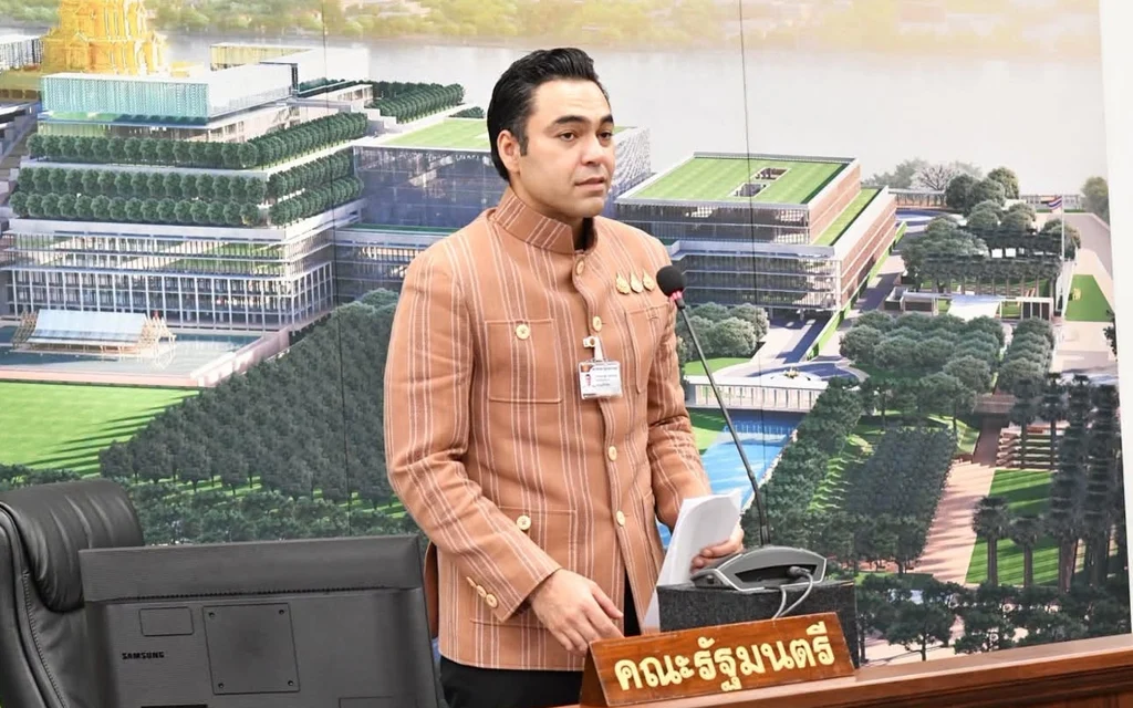 A man in a striped jacket speaking at a podium.