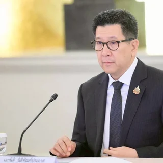Ekniti Nitithanprapas sitting at a table during a meeting.