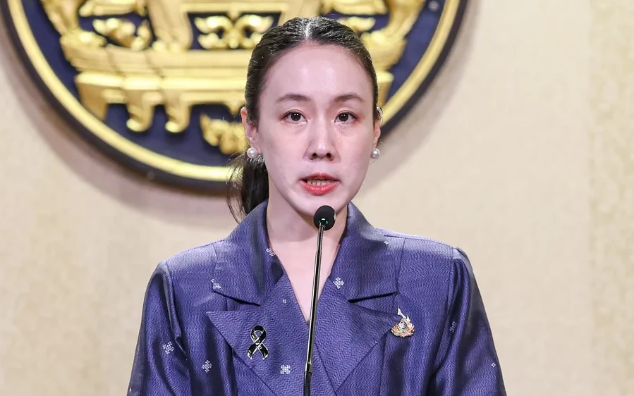 A woman speaking at a podium with a government emblem behind.