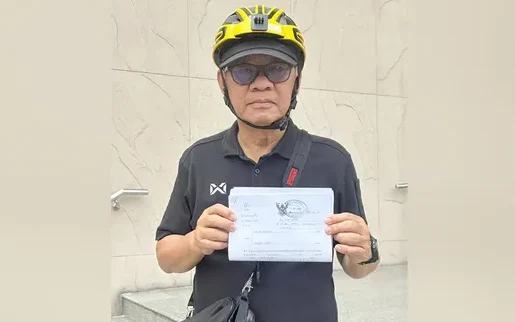 Somchai Srisutthiyakorn holding a legal document.