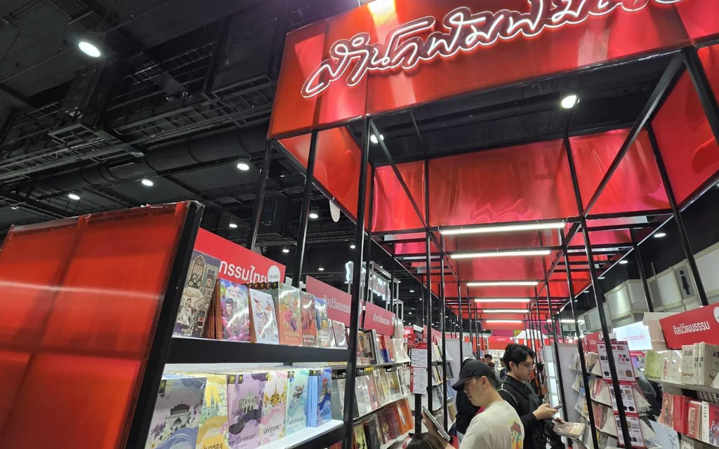 Shoppers browse book displays beneath red signage at a Bangkok book expo.