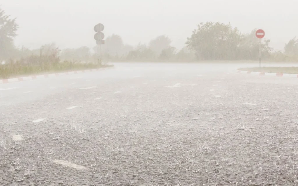 Heavy rain falling on an empty road.
