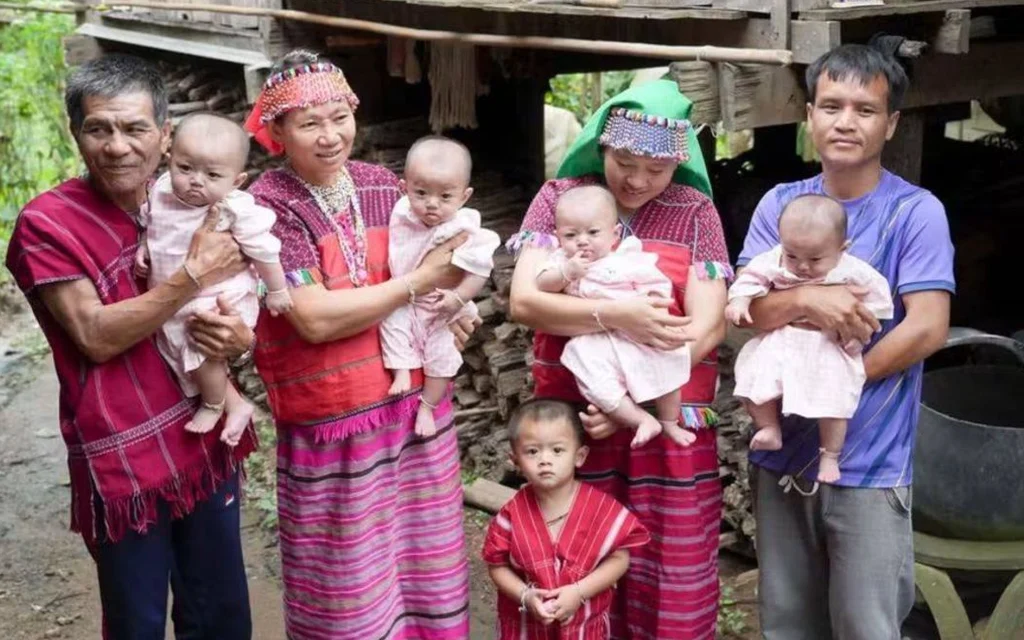 A family holding several babies in traditional clothing
