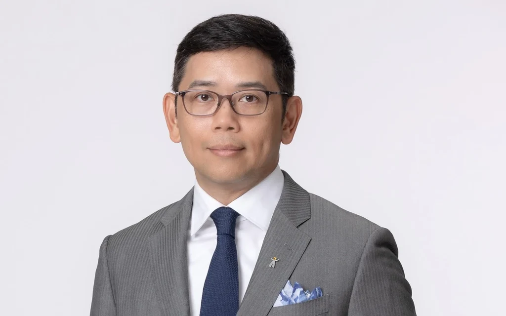 Portrait of a man wearing glasses and a gray suit