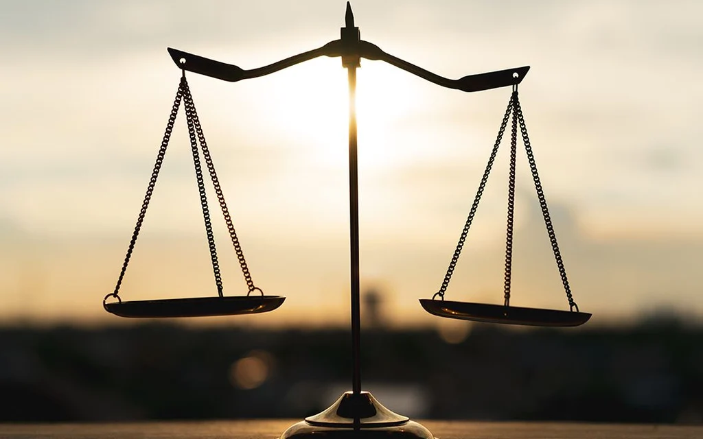 Silhouette of balanced scales against a sunset