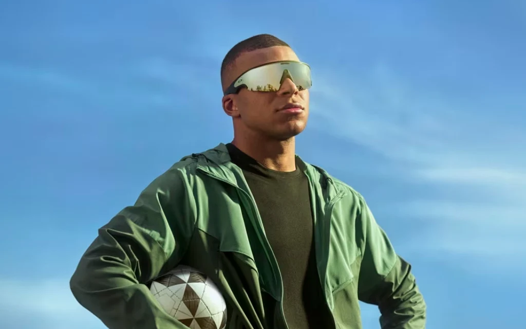 Kylian Mbappe wearing sunglasses and holding a soccer ball.