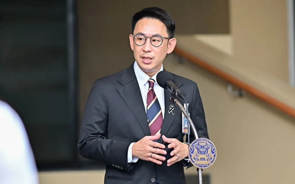 A suited man speaks at a microphone during a press briefing.