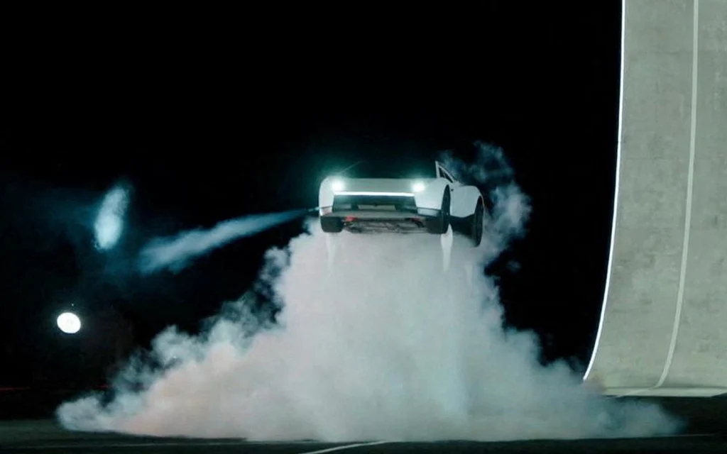 A white Tesla Roadster performing a stunt with smoke.