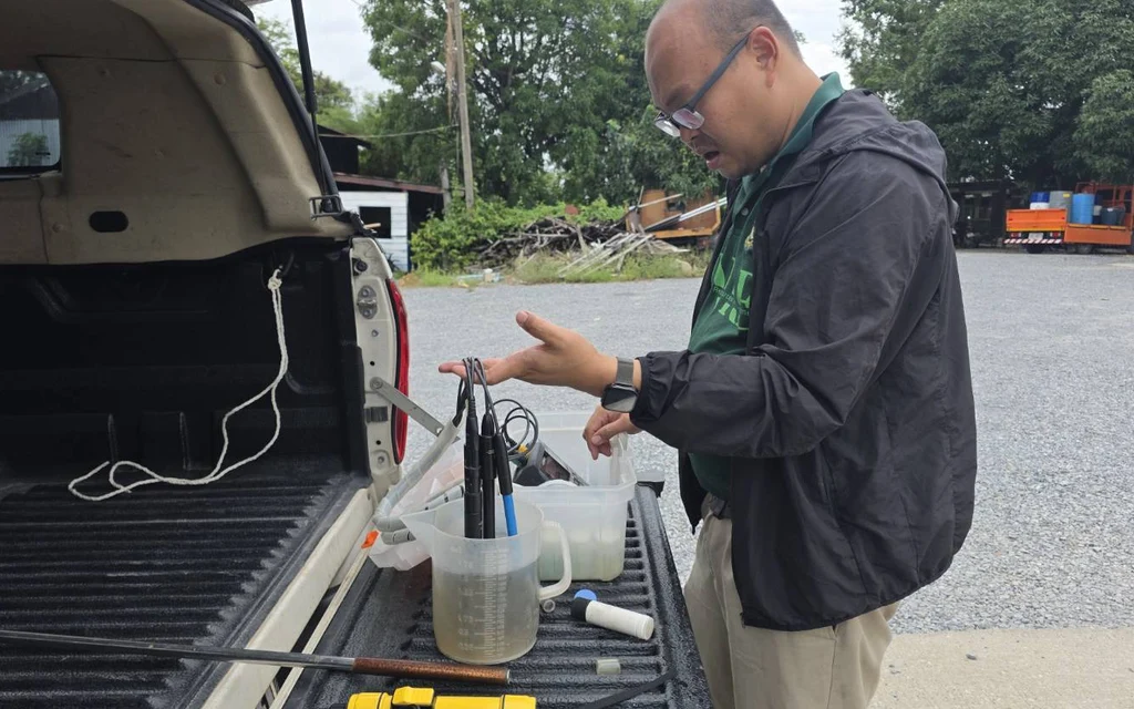 A man testing water quality samples on the back of a truck.
