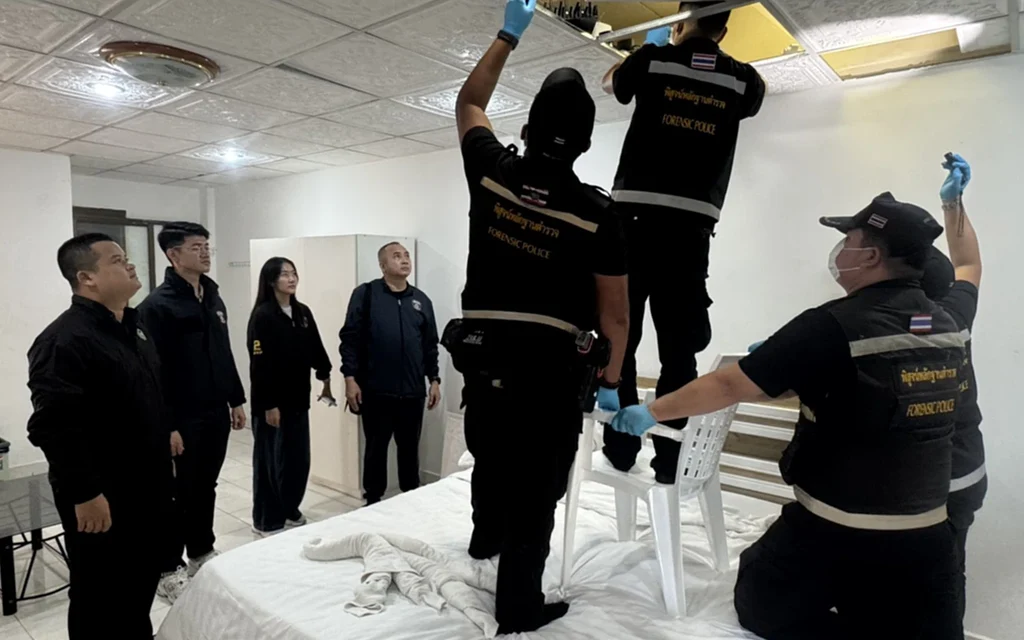 Police inspect ceiling during a raid on suspected call center equipment.