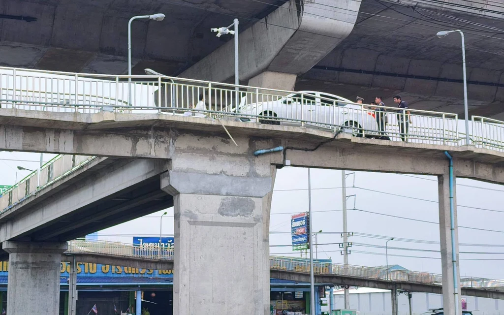A white car stuck on a pedestrian motorcycle bridge.