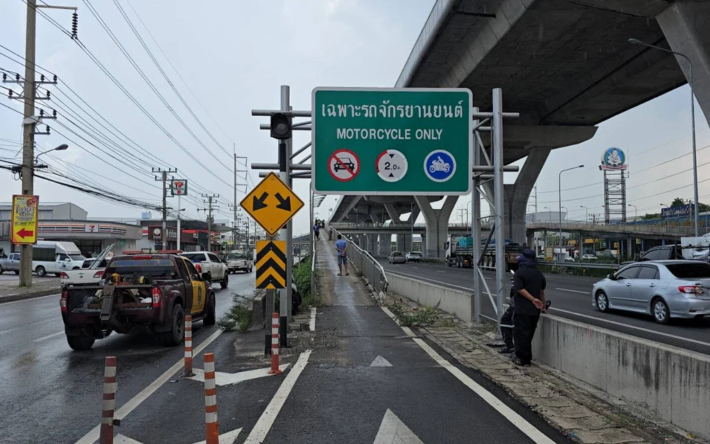 A motorcycle only bridge sign with traffic and a tow truck.