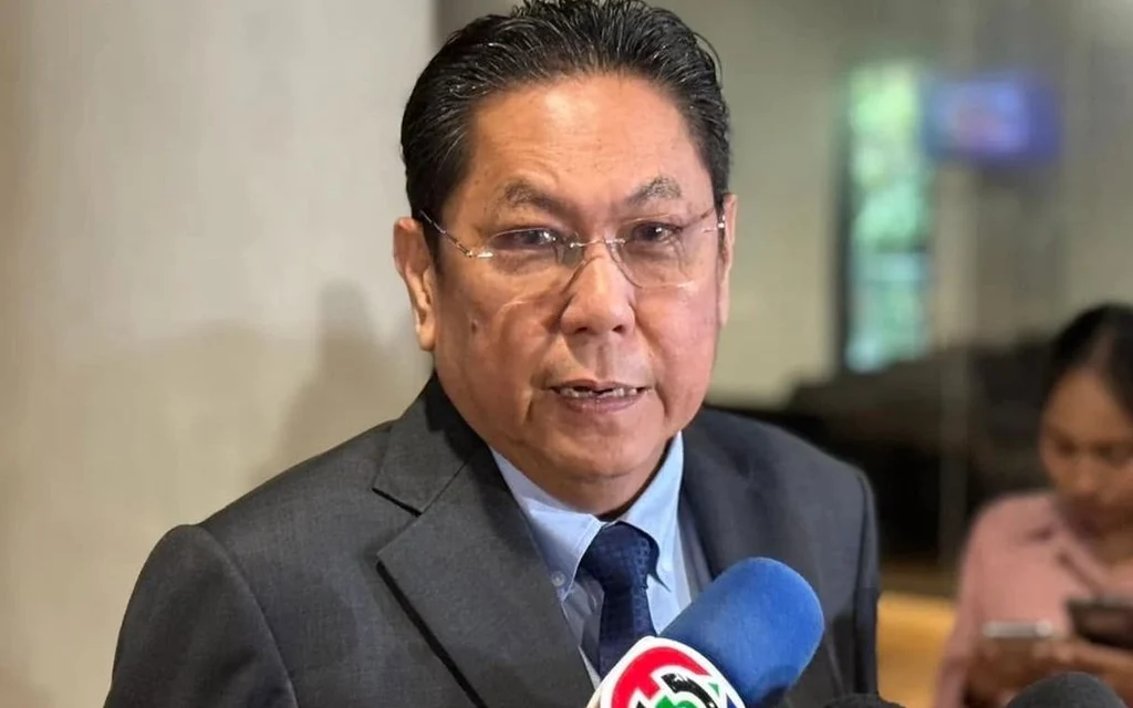A politician speaks to reporters as microphones are held toward him.