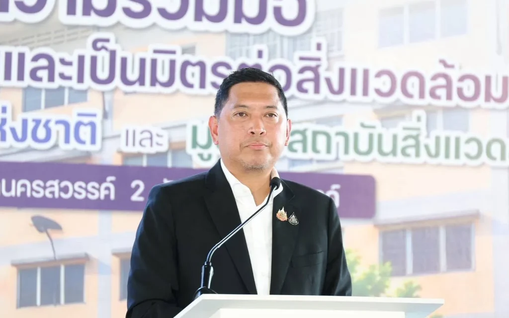 Minister speaks at a podium during an eco-friendly housing project launch.