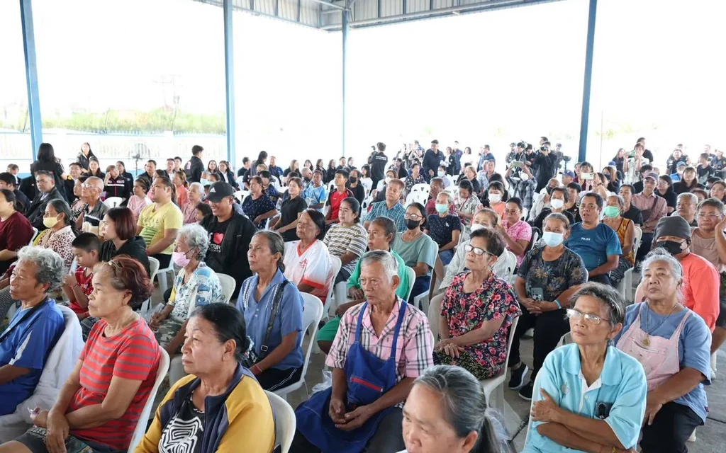 Crowd of residents seated inside a covered hall at a community meeting