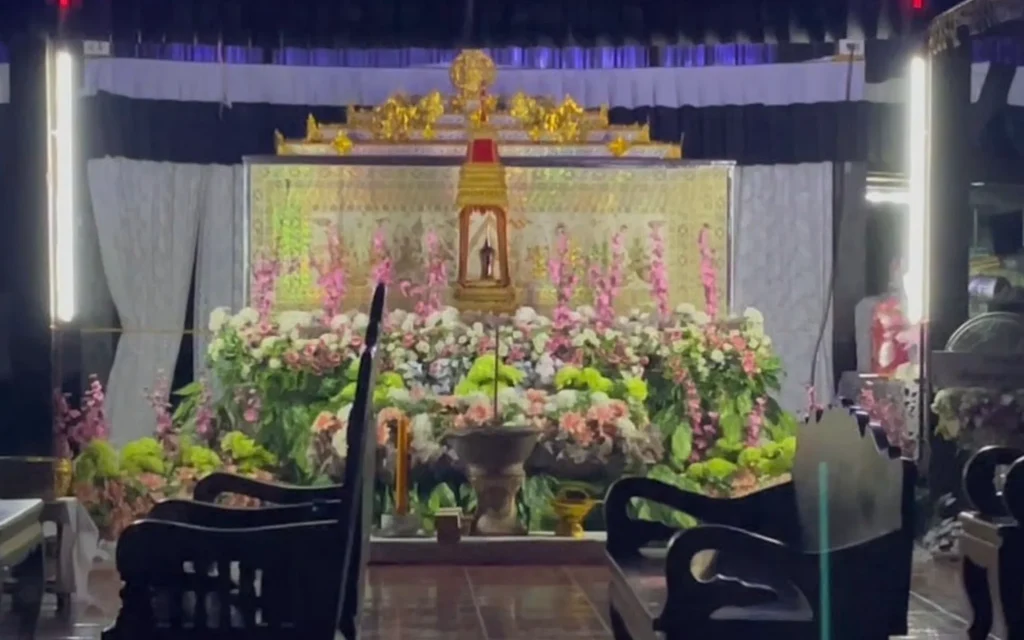 A decorated funeral altar with flowers in a Thai temple.