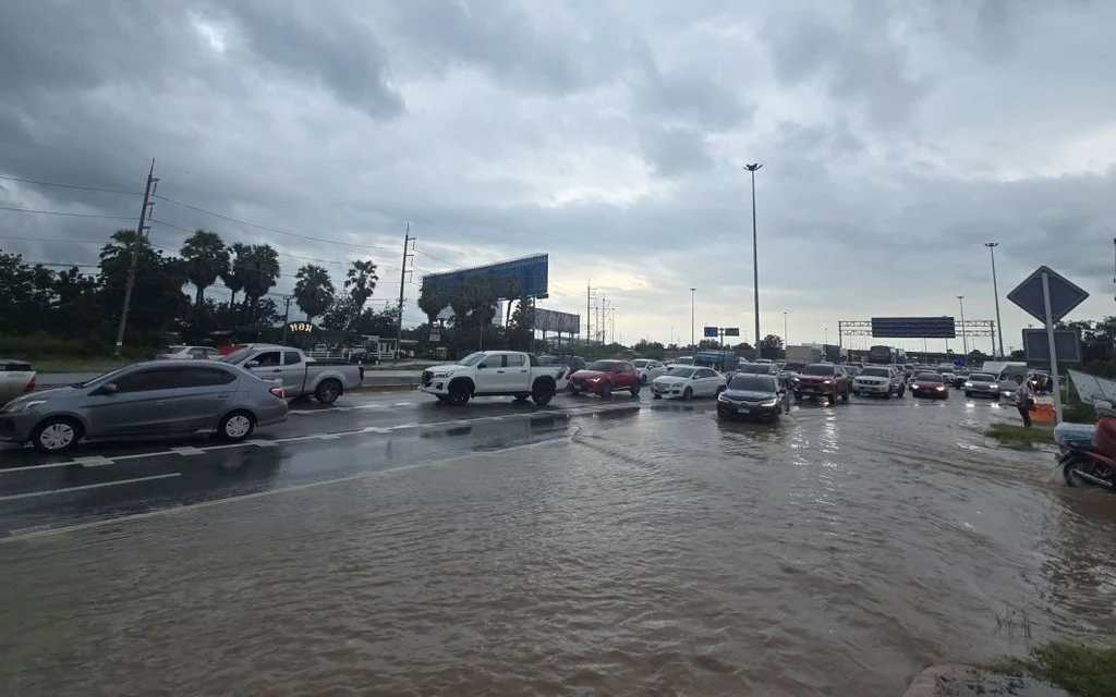 Cars driving through a flooded road during heavy rain.