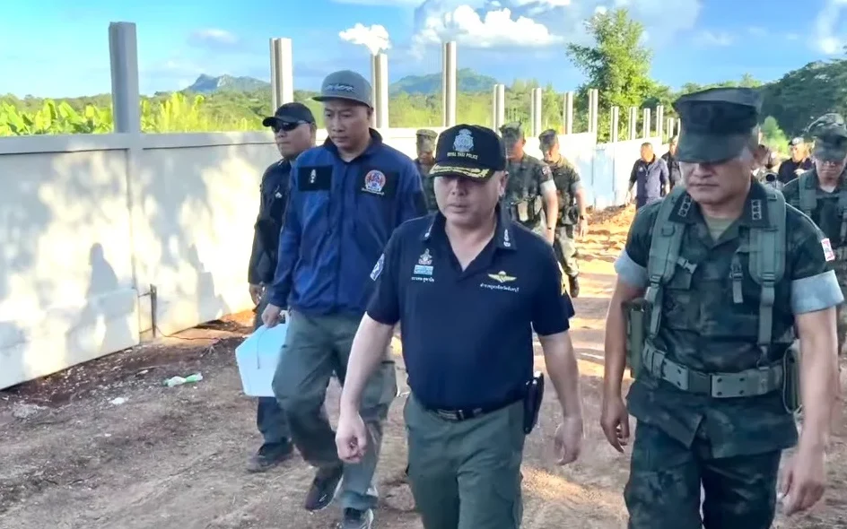 Officials and personnel inspect a border fence construction site.