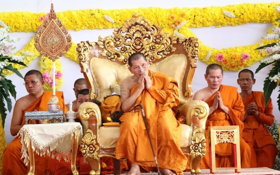 Luang Pu Sila Sirichanto sitting on a chair during a ceremony.