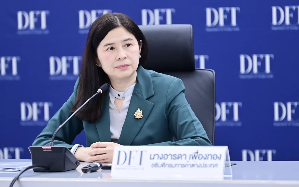 Trade official seated at a press conference table with microphone.