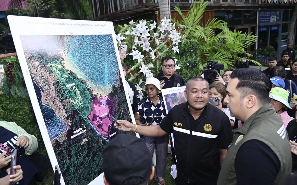 Officials discuss a land-use map during a Phuket inspection.