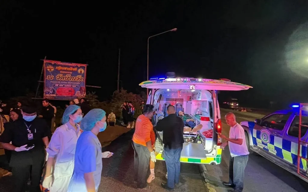 Emergency responders and bystanders gather around an ambulance at night.