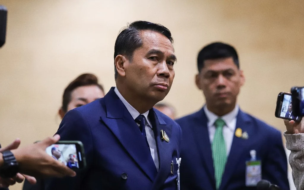 Thai politician surrounded by reporters holding smartphones to record him.