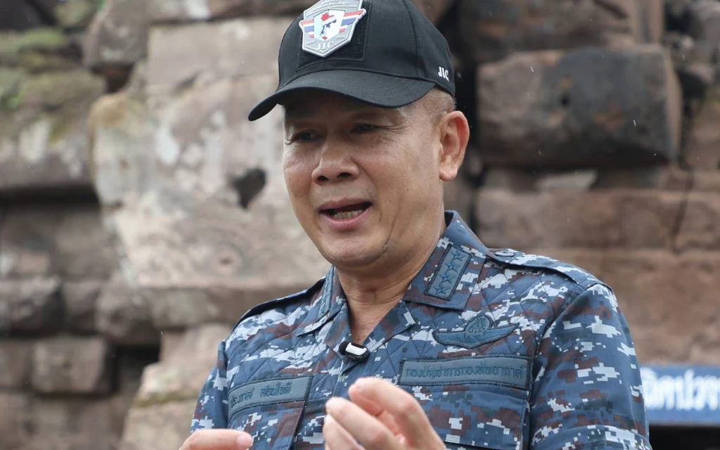 A uniformed military official speaks in front of stone ruins.