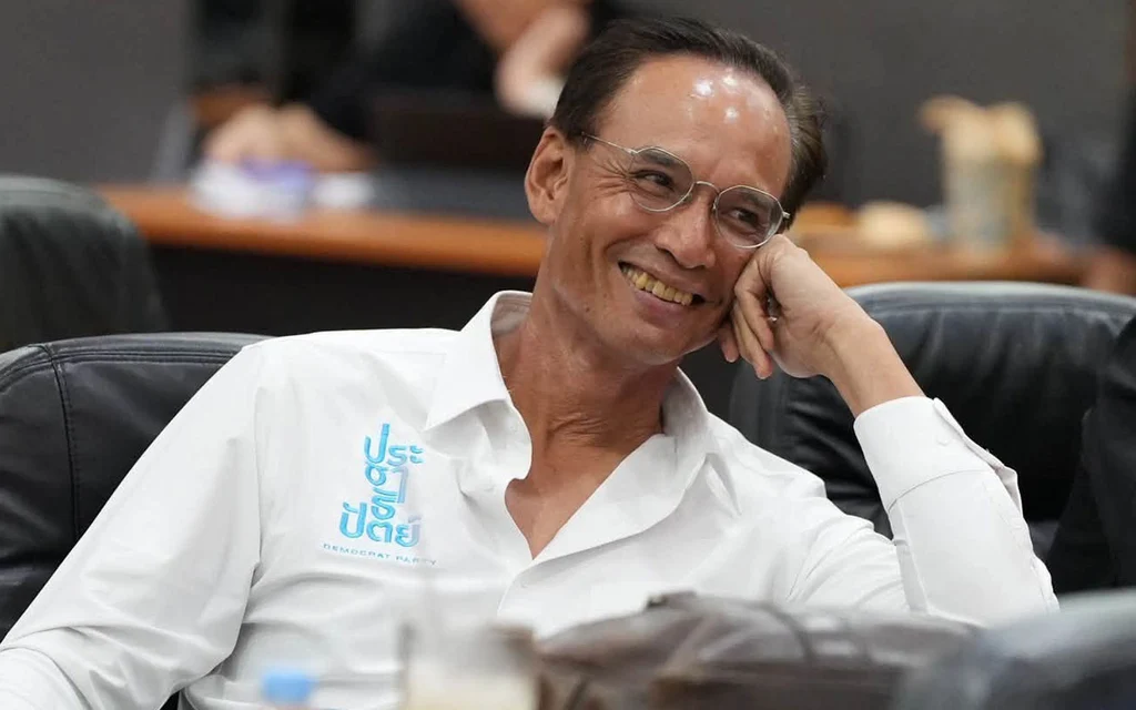 A smiling man in a white shirt sits in a meeting room.