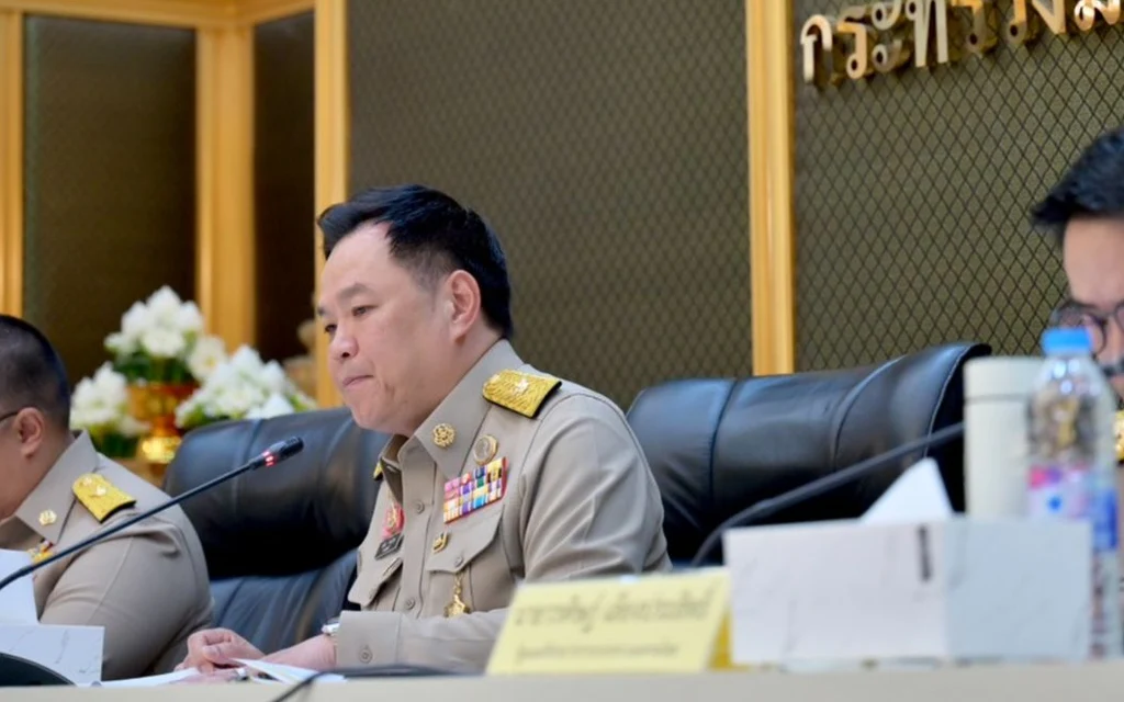 Thai government officials in uniform attend a meeting at a conference table.