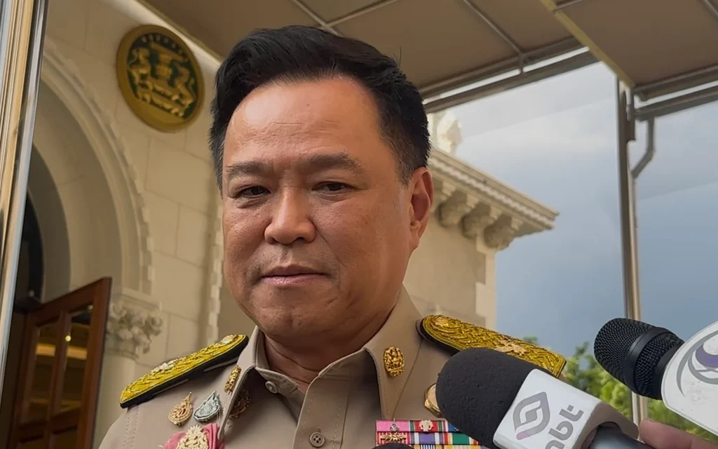 A uniformed official speaks to reporters outside a building.