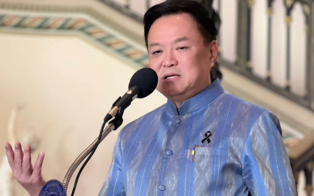 Anutin speaks at a microphone in a blue traditional-style jacket.