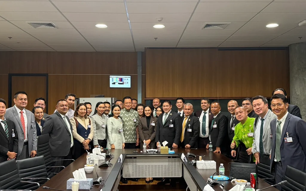 Politicians and officials pose around a conference table in a meeting room.