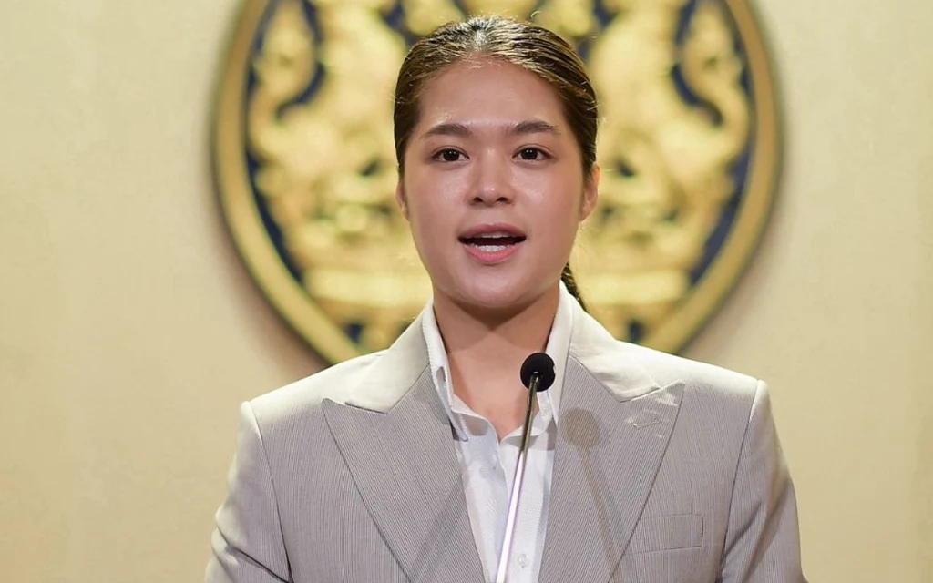 A woman speaks at a podium in front of an official emblem.