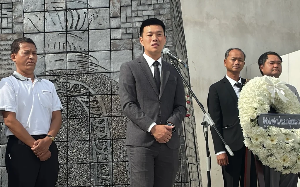 Political leaders standing in front of a monument with a wreath.