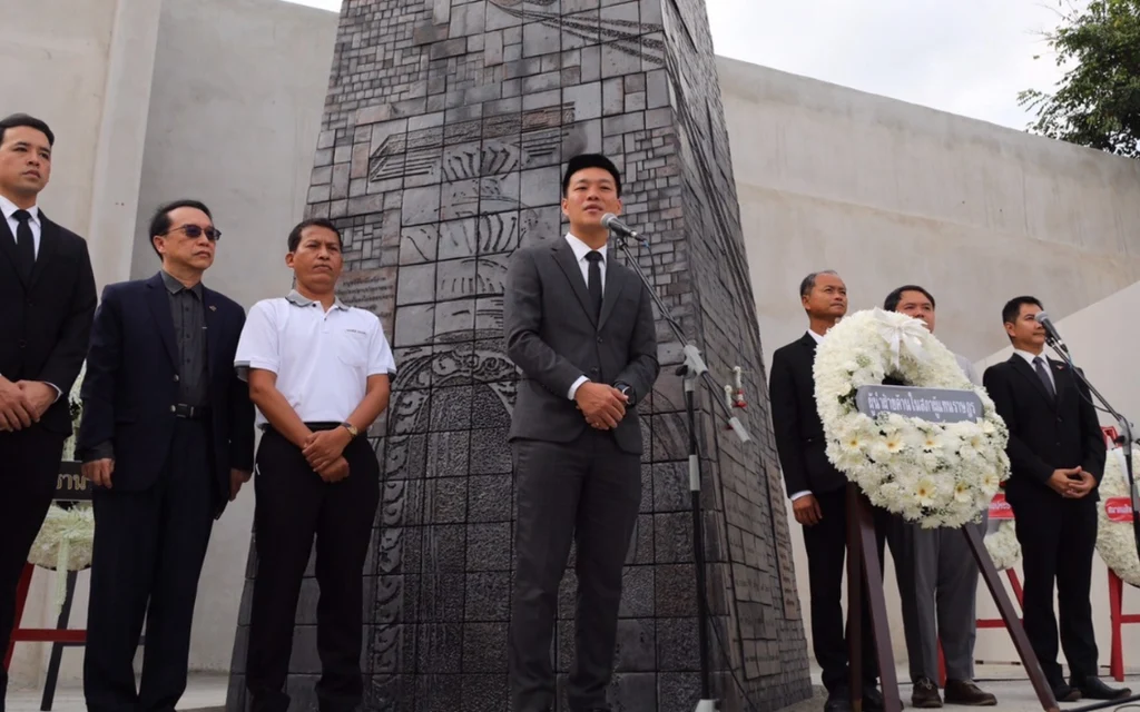 Political figures standing before a monument during a commemorative ceremony.