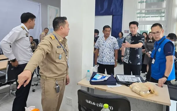 Officials and staff gather around a table in a meeting room.