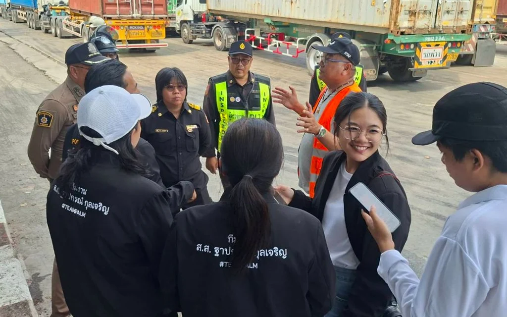 Officials and team members inspecting traffic conditions near parked container trucks.