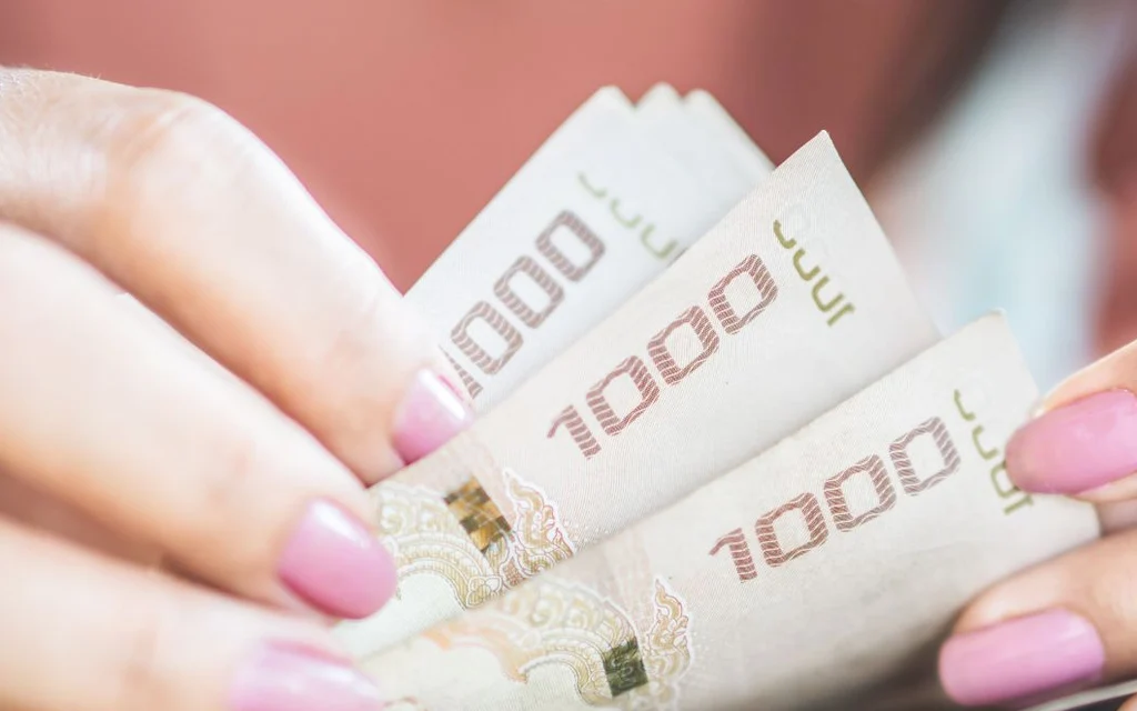 Hands holding several Thai 1,000-baht banknotes