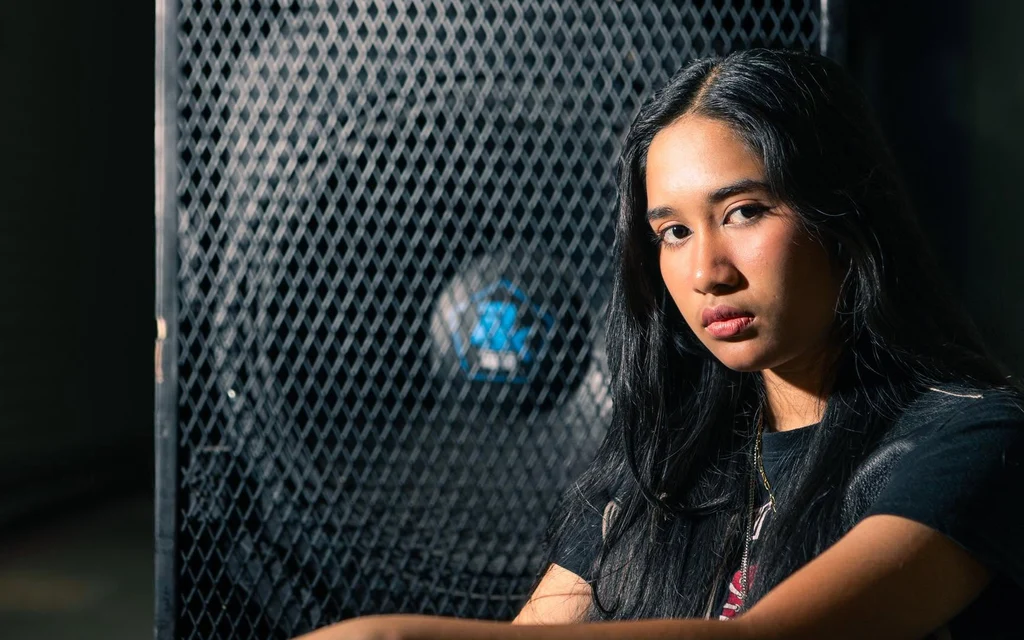 Woman poses in front of a metal mesh backdrop.