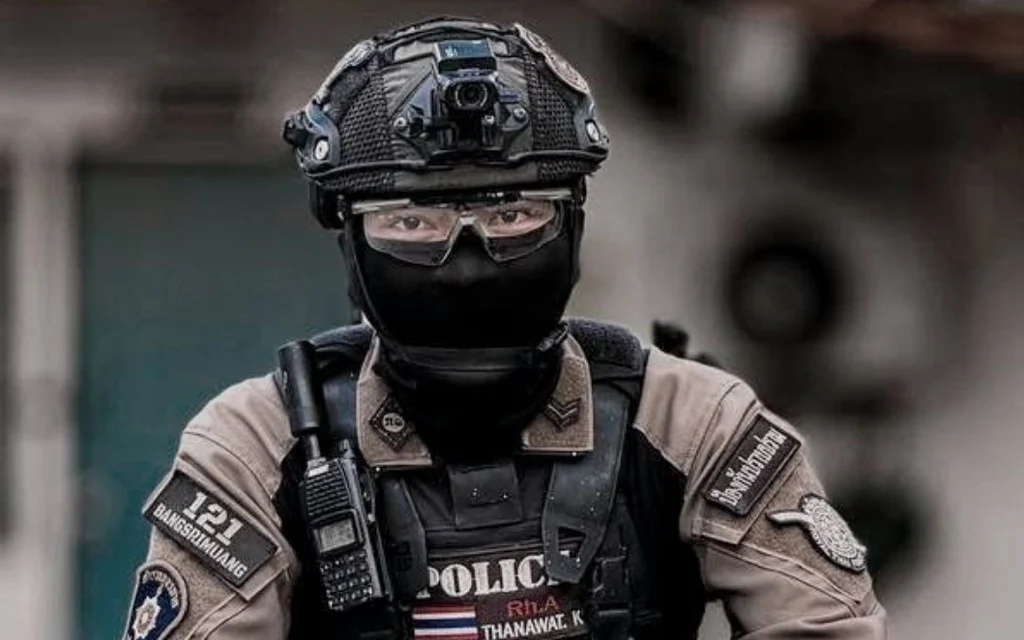 Masked police officer wearing tactical gear and helmet with mounted camera
