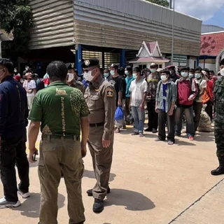 A group of people standing at a border checkpoint