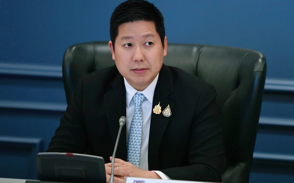 A man in a suit sitting at a desk with a nameplate.