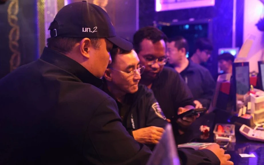 Officials inspect a KTV venue counter during a nighttime raid.