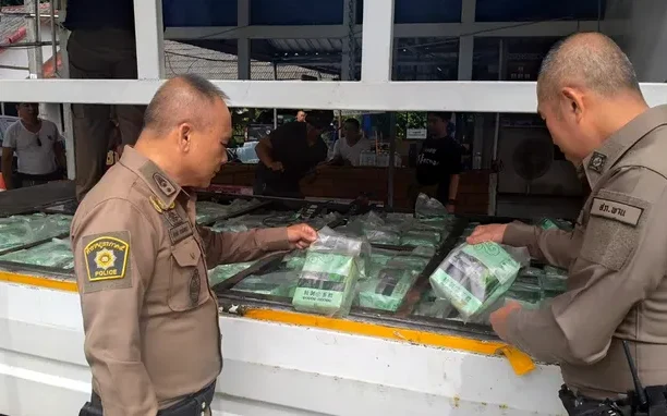 Thai police officers inspecting seized packages of crystal methamphetamine on a truck.